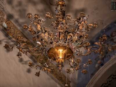 Dal centro del soffitto cade poi un raffinato candelabro settecentesco adornato da applicazioni in bronzo dorato a motivo floreale